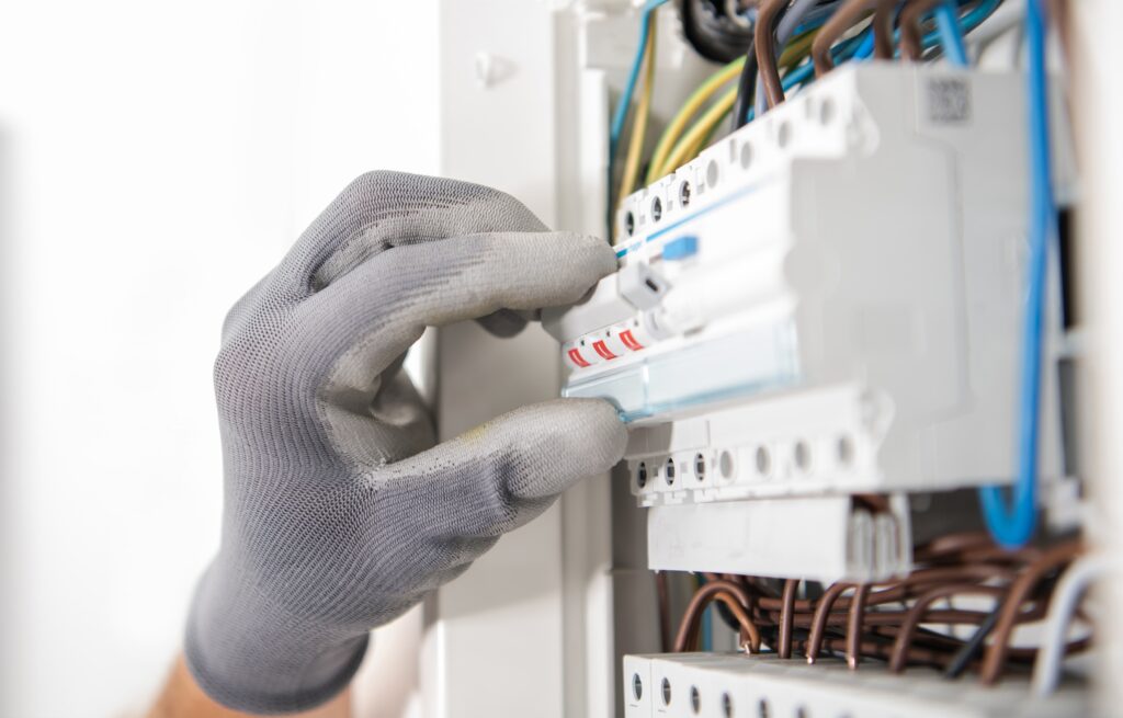 Electrical Services - gloved hand of an electrician working on switchboard